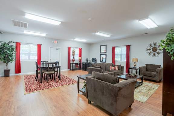 A living room with a grey couch, a wooden floor, and a rug at Greylin Ridge Apartments, North Carolina