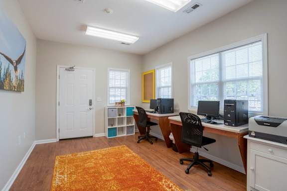 A room with a white door, a yellow door, and a desk with a computer and printer at Greylin Ridge Apartments, North Carolina