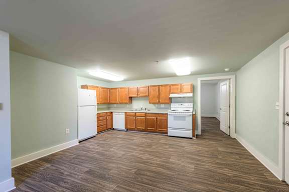 A kitchen with wooden cabinets and white appliances.at Kinston Hotel Apartments, Kinston North Carolina