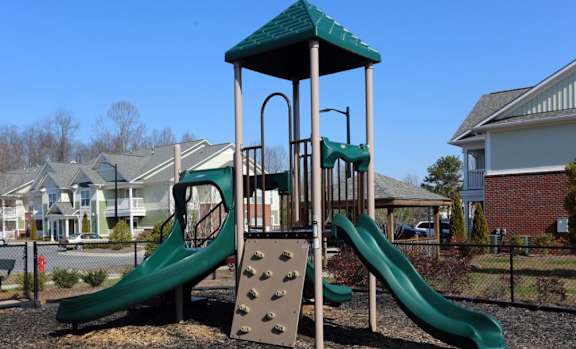 Playground with a green slide and a wooden structure at Cooper Terrace in Elkin