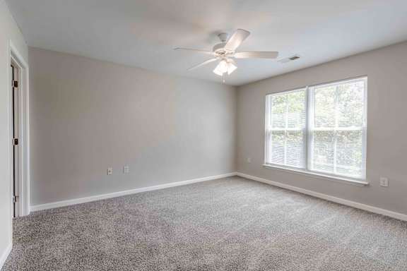 A room with a ceiling fan and a window with blinds.