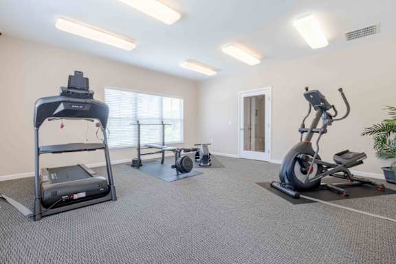A spacious gym with a treadmill, elliptical trainer, and stationary bike.