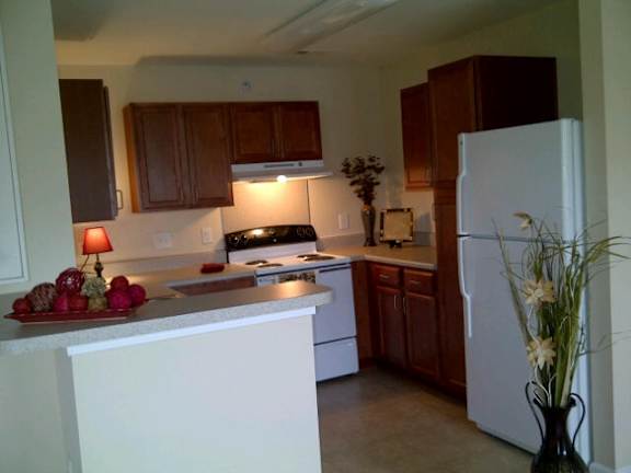 A kitchen with a white refrigerator and wooden cabinets at Greylin Ridge Apartments, North Carolina