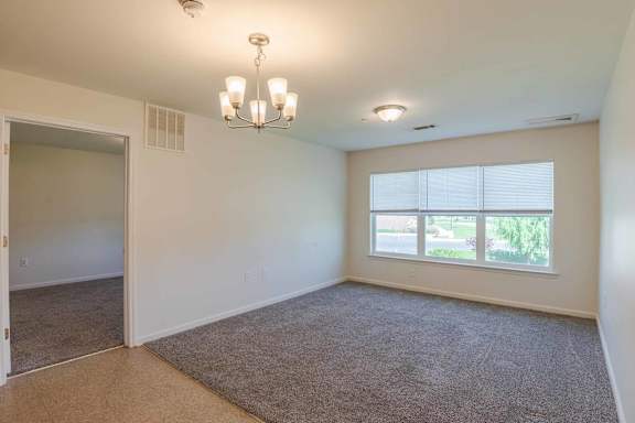 A room with a carpeted floor and a chandelier hanging from the ceiling. at Mountain Laurel Apartments, Staunton, VA