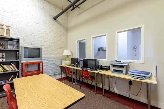 A room with a desk, chairs, and computers. at Nantucket Lofts Apartments, Kinston, NC