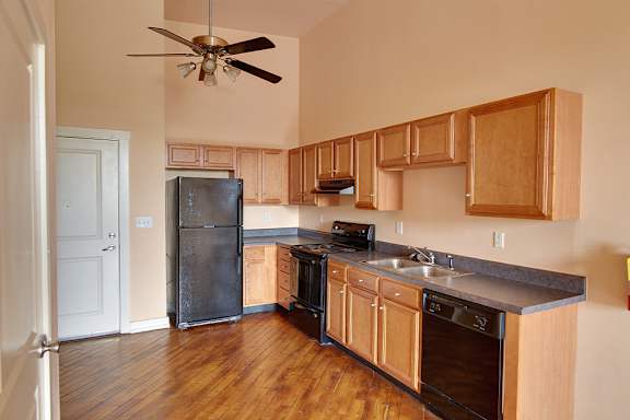 A kitchen with wooden cabinets and a black refrigerator at Nantucket Lofts Apartments, Kinston