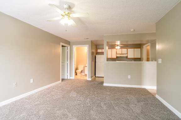 A living room with a carpeted floor and a ceiling fan.at Spaulding Woods Apartments, Marion, 28752