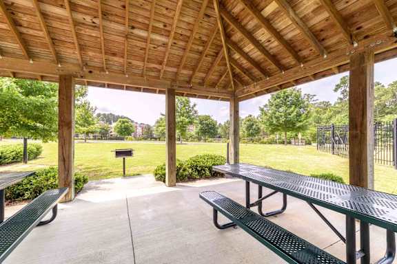 A wooden pavilion with green benches and a fence in the background. at The Grande at Granite Falls LLC Apartments, Rolesville, NC, 27571