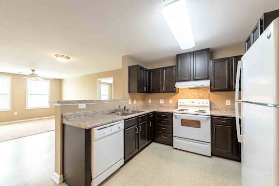 A kitchen with a white refrigerator, a white stove, and a white dishwasher. at The Grande at Granite Falls LLC Apartments, Rolesville, NC