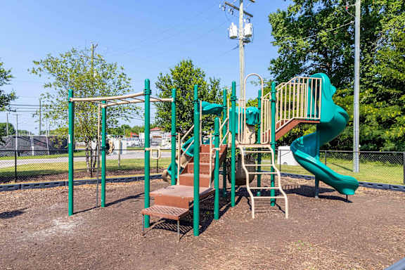 A playground with a green slide and a brown bench at The Shire Apartments, Virginia