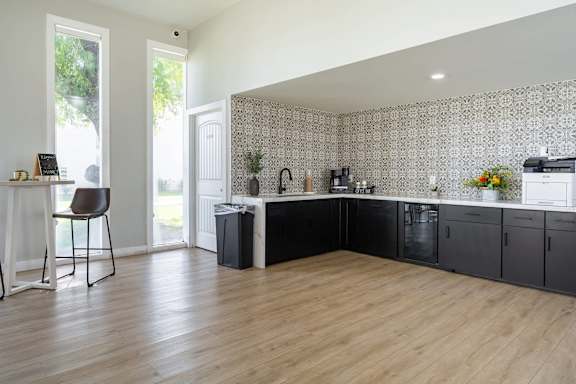 A kitchen with black cabinets and a patterned wallpaper.