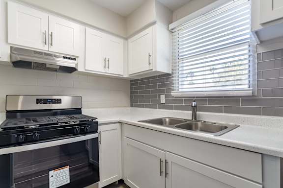 A modern kitchen with a stove, sink, and cabinets.