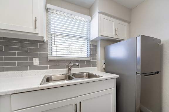 A kitchen with a sink and a refrigerator.
