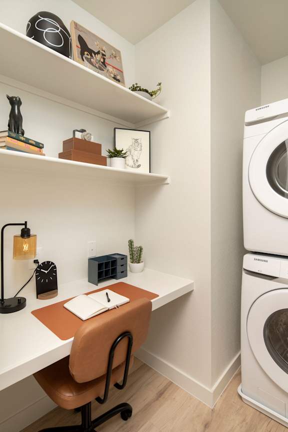 A small room with a desk, chair, and a washing machine.