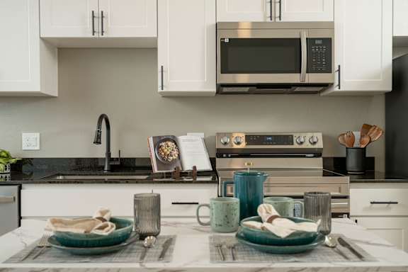 A modern kitchen with a black countertop and white cabinets.