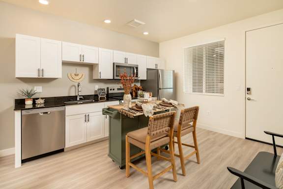 A kitchen with a table and chairs in the middle.
