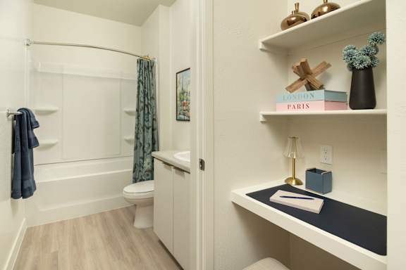 A bathroom with a toilet, sink, and a window with a curtain.