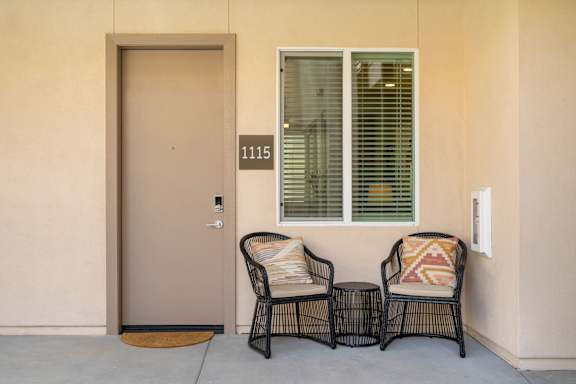 Two chairs with pillows are placed on a patio.