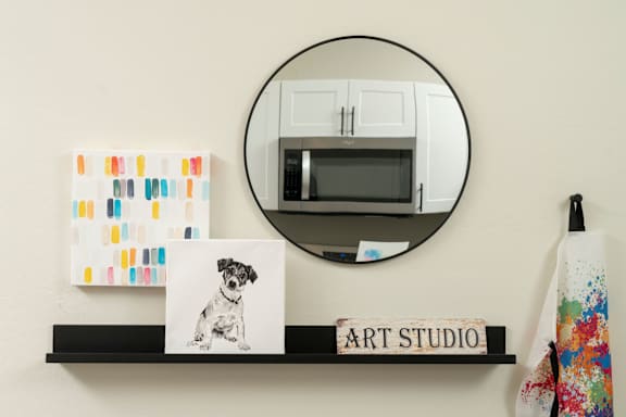 A picture of a dog is on a shelf under a mirror.