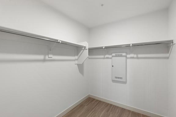 A white closet with a white door and a white shelf.