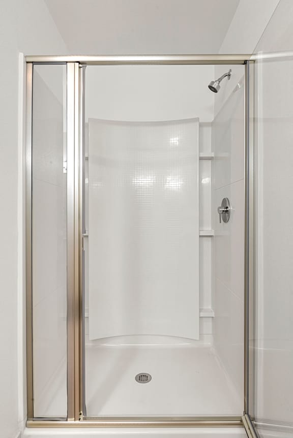 A white bathroom with a glass shower door.