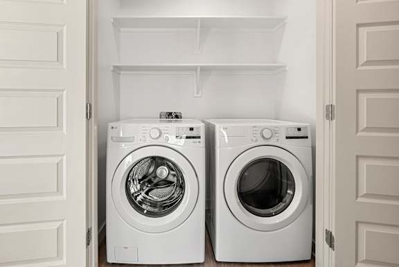 Two white front load washing machines in a laundry room.