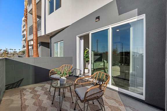 A patio with a table and chairs is in front of a modern building.