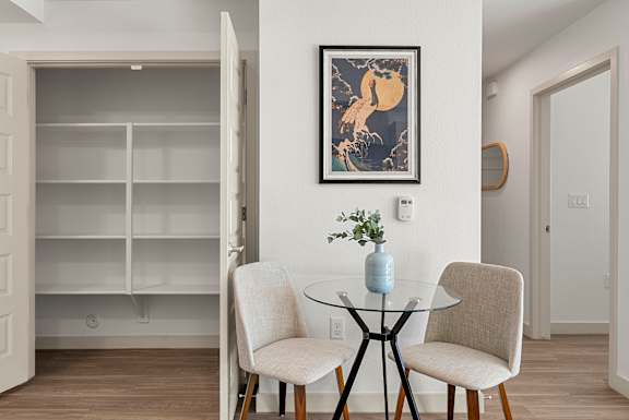 A dining room with a glass table and two chairs.