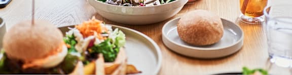A table with a bowl of salad, two sandwiches, and a glass of drink.