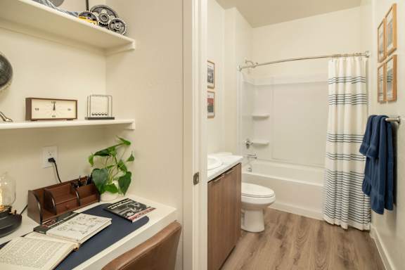 A bathroom with a toilet, sink, and a chair.