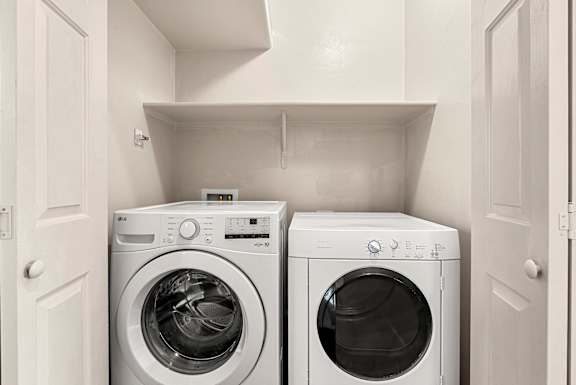 Two front loading washing machines in a small laundry room.