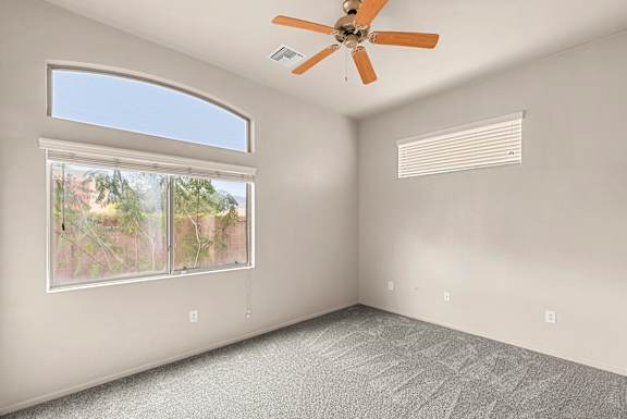 A room with a ceiling fan and a window with blinds.
