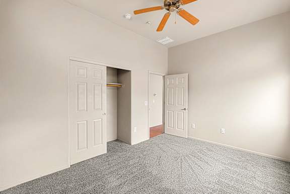 A room with a ceiling fan and two doors.