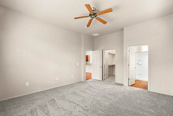 A room with a ceiling fan and carpeted floor.