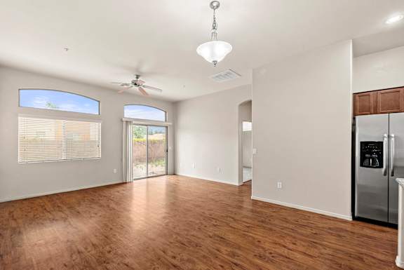A spacious living room with wood flooring and a ceiling fan.