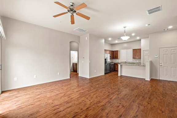 A room with a ceiling fan and wooden floors.