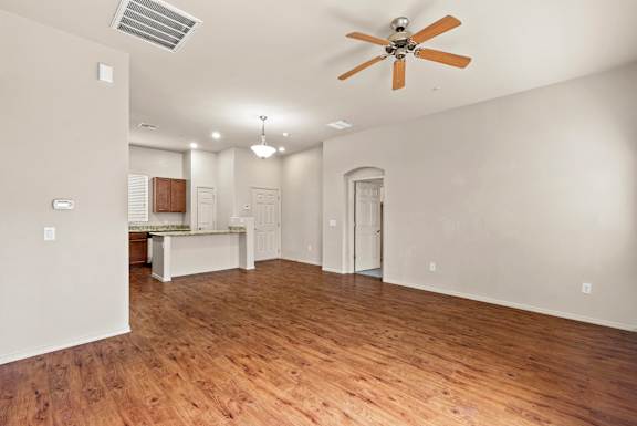 A room with a ceiling fan and wooden floors.