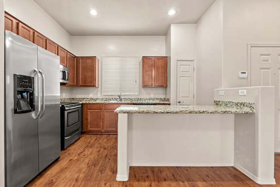 A kitchen with a stainless steel refrigerator and wooden cabinets.