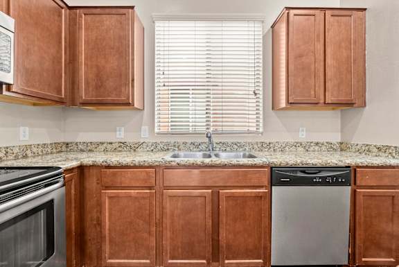 A kitchen with brown cabinets and a granite countertop.