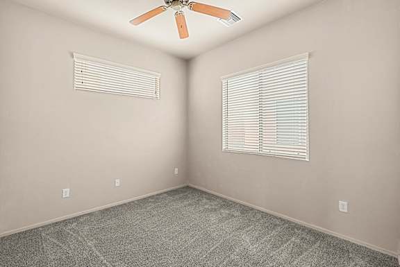 A room with a ceiling fan and a window with blinds.