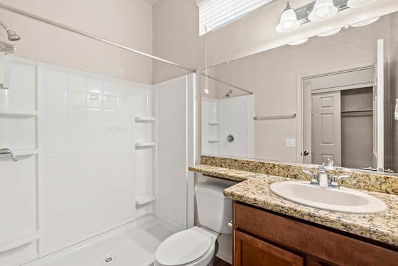 A white bathroom with a sink, toilet, and shower.