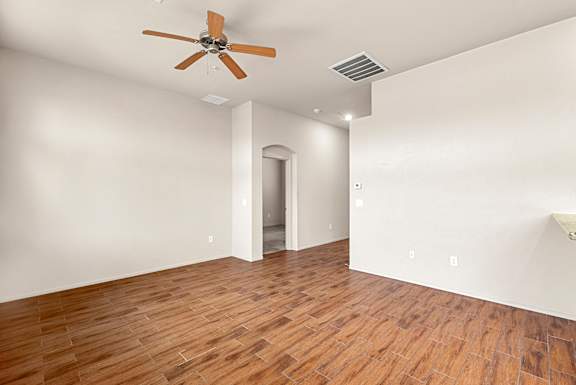 A room with a ceiling fan and wooden flooring.