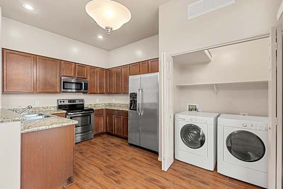 A kitchen with a refrigerator, oven, and washing machine.