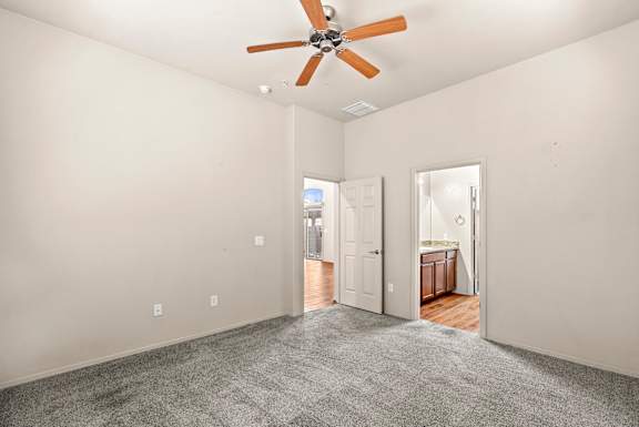 A room with a ceiling fan and carpeted floor.