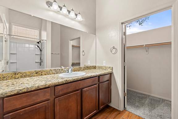 A bathroom with a granite countertop and wooden cabinets.