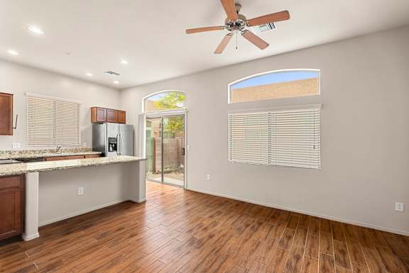 A kitchen with a refrigerator, sink, and a fan.