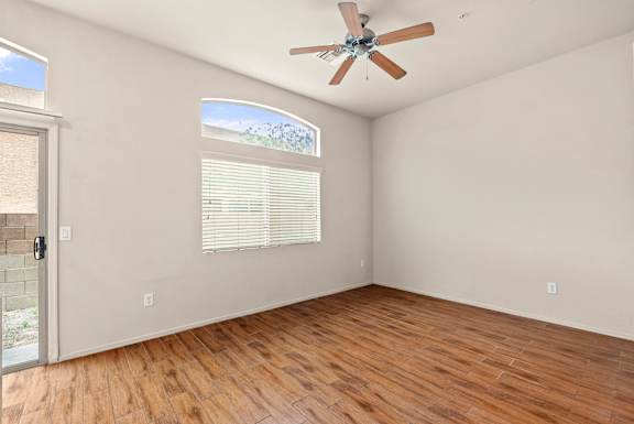 A room with a ceiling fan and a window with blinds.
