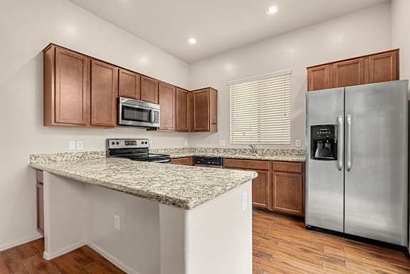 A kitchen with a granite countertop and stainless steel appliances.