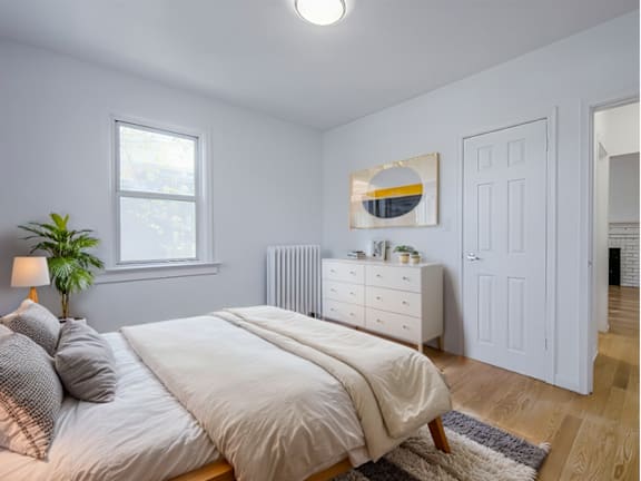 A bedroom with a bed, nightstand, and a painting on the wall.