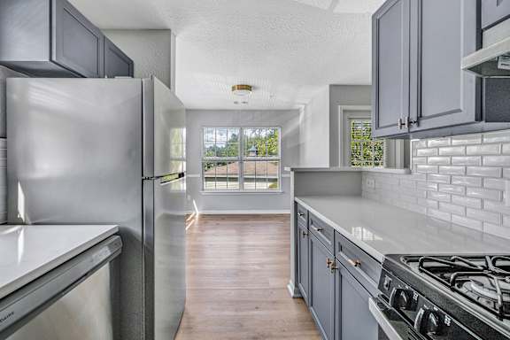 A modern kitchen with a stainless steel refrigerator and a wooden floor. at Ardenwood Apartments, North Haven, 06473
